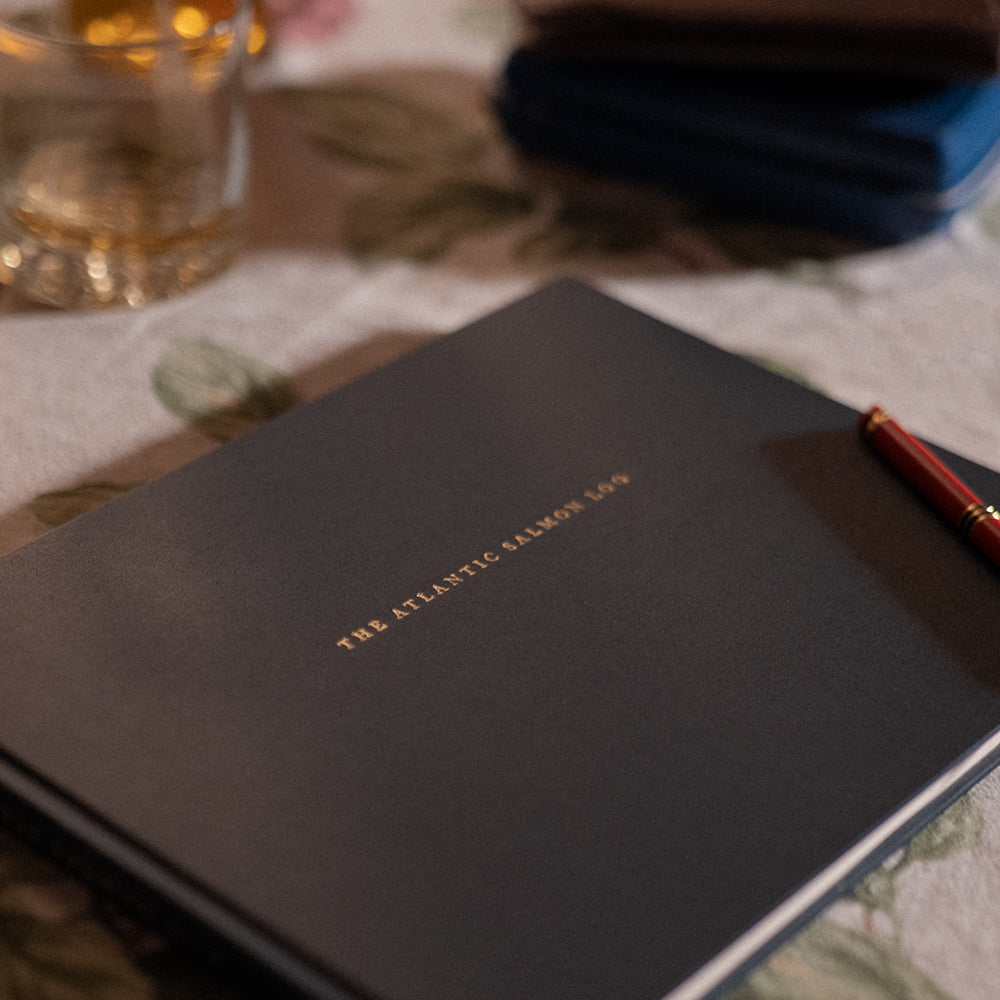 Close up image of the front cover of the Atlantic Salmon Log on a table in a cottage and a red pen.