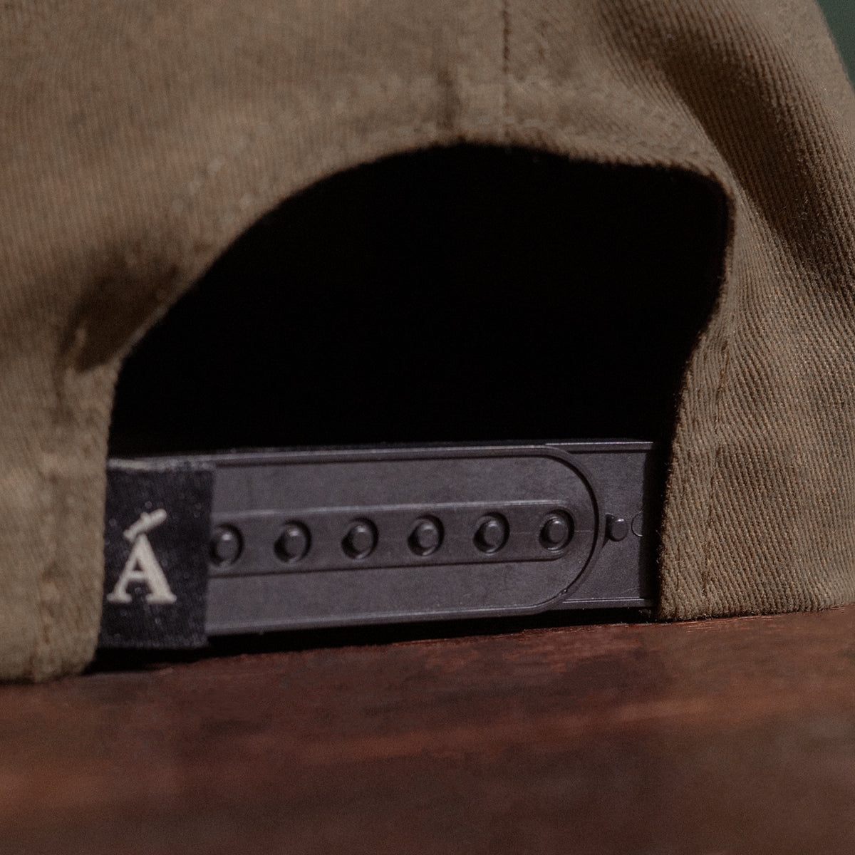 Close-up of an olive cap with Ánadröm logo on the back