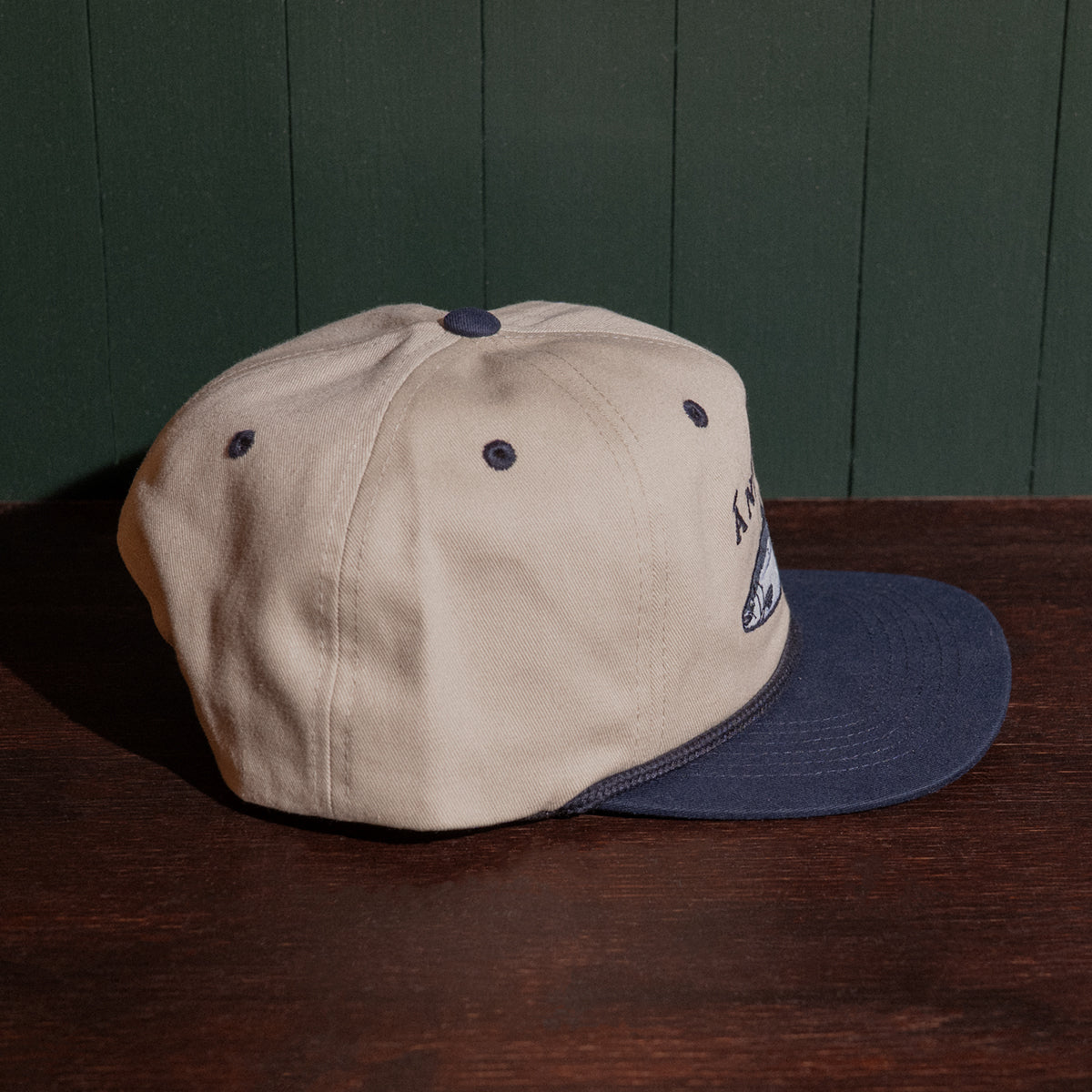 Stone and navy cap on a wooden surface with a dark green panel background