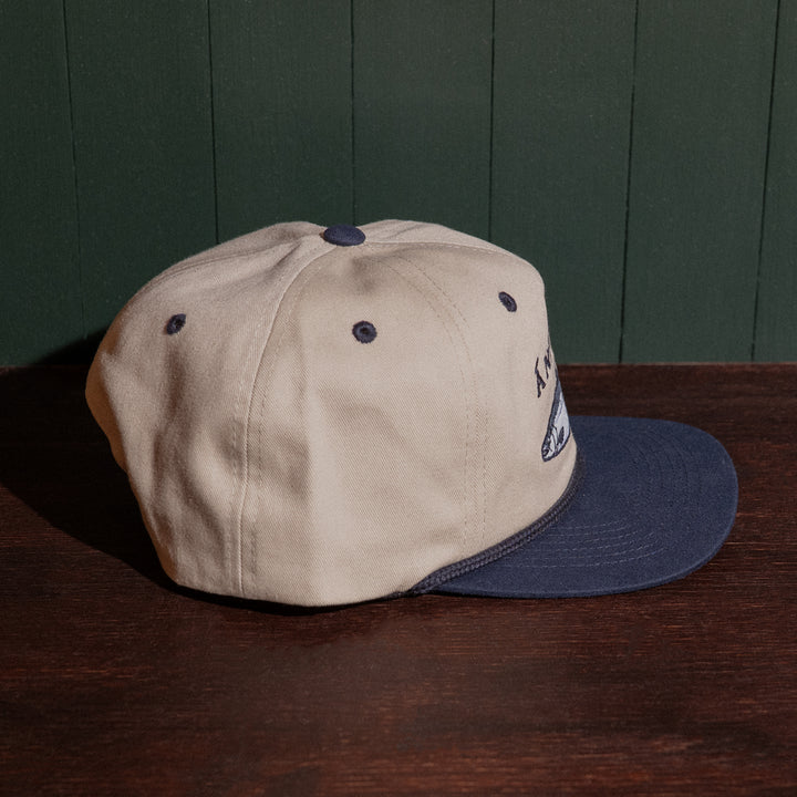 Stone and navy cap on a wooden surface with a dark green panel background