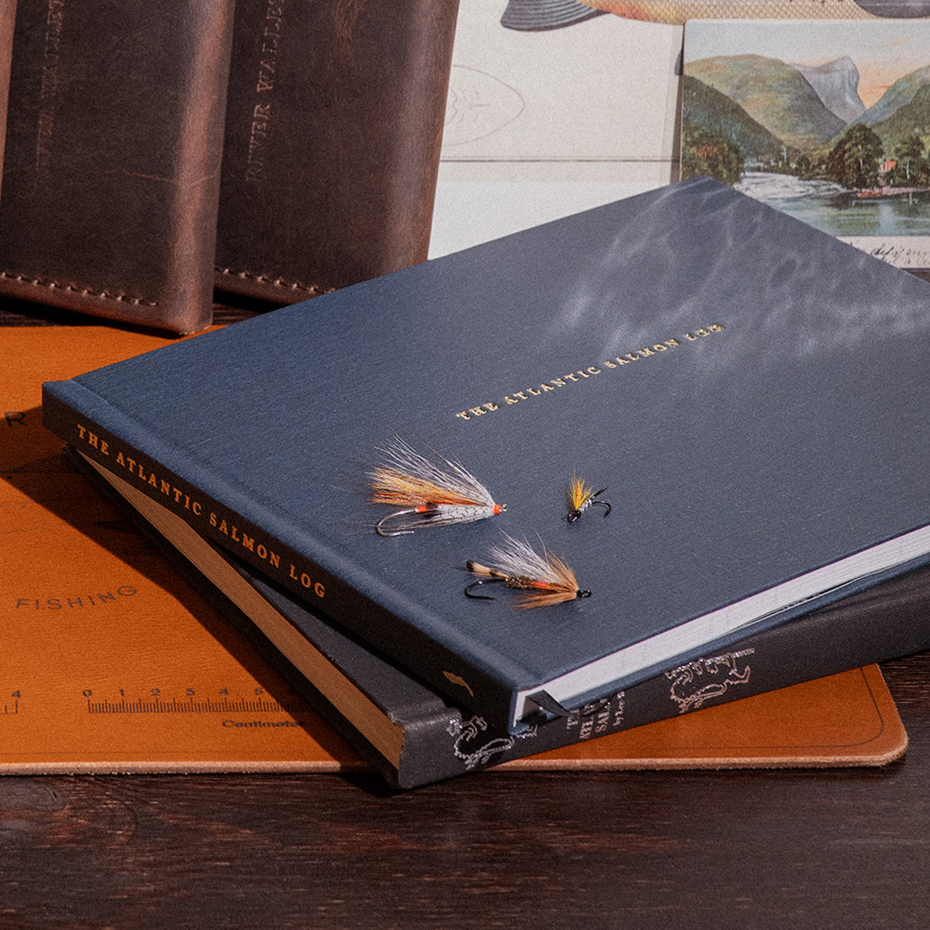 Front cover of the Atlantic Salmon Log, a handcrafted fishing journal for salmon anglers with Atlantic salmon flies on top.