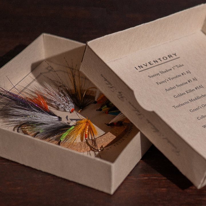 Ánadröm Selection box open beside inventory lid listing Sunray Shadow, Fanny's Favorite, and other Atlantic salmon flies.