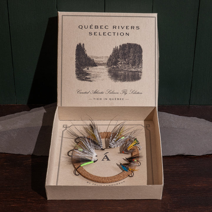 Ánadröm Québec Rivers Selection box open, seven hand-tied Atlantic salmon flies on cork insert, river engraving on lid.